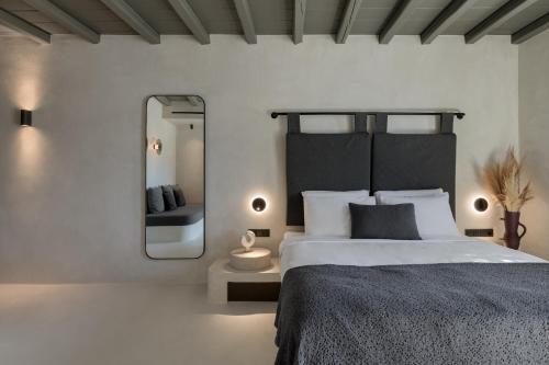 a bedroom with a large bed and a mirror at Rocabella Mykonos Hotel in Agios Stefanos