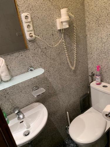 a bathroom with a toilet and a phone on the wall at Kalmár Panzió in Budapest