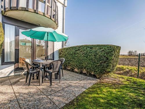 a table and chairs with an umbrella on a patio at Apartment Sirius with parking and shared pool by Interhome in De Haan