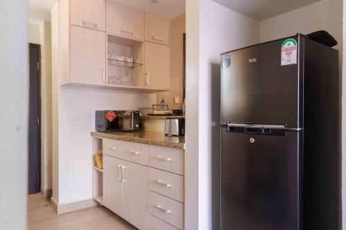une cuisine avec un réfrigérateur noir et des armoires blanches dans l'établissement Wellivia Suites Serviced Apartments, à Nairobi