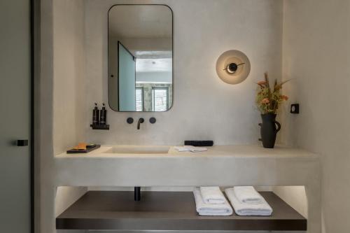a bathroom with a sink with a mirror and towels at Rocabella Mykonos Hotel in Agios Stefanos