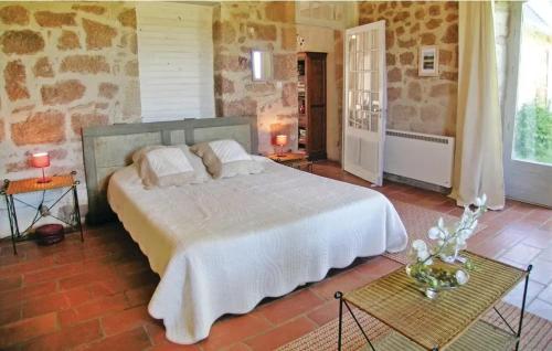 une chambre avec un grand lit et un mur en pierre dans l'établissement Maison accueillante avec vue sur le jardin à Villac, à Villac