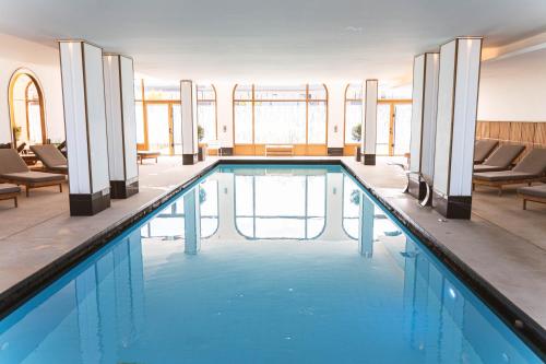 une grande piscine avec des chaises et des tables dans un bâtiment dans l'établissement L'intemporel plage - Malo'Cation, à Dunkerque