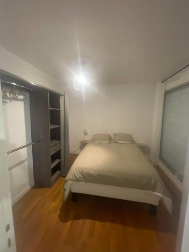 une chambre blanche avec un lit et un placard dans l'établissement Appartement face au port, à Grandcamp-Maisy