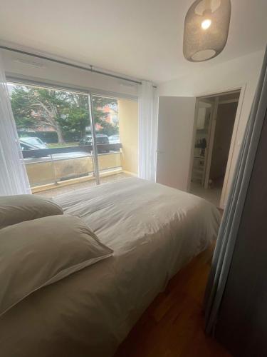 une chambre avec un lit et une grande fenêtre dans l'établissement Appartement face au port, à Grandcamp-Maisy