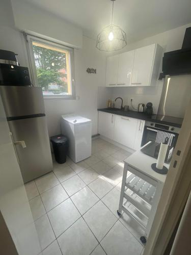 Elle comprend une petite cuisine avec des placards blancs et une fenêtre. dans l'établissement Appartement face au port, à Grandcamp-Maisy