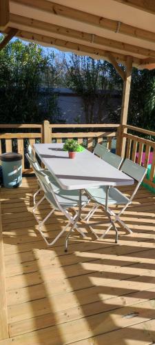 une table et des chaises blanches sur une terrasse en bois dans l'établissement mobil home chaleureux et idyllique, à Lattes