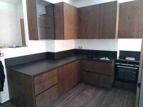 a kitchen with wooden cabinets and a black counter top at Lakes of Fusine three border area in Fusine in Valromana
