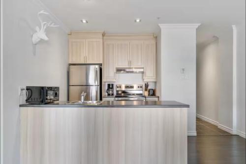 a kitchen with white cabinets and stainless steel appliances at INITIAL - MOOSE - Chutes-Montmorency in Boischâtel