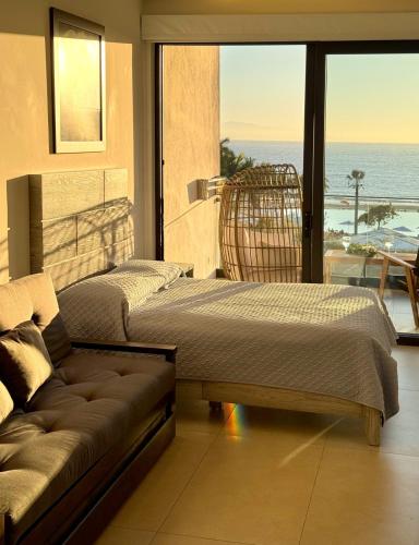 two beds and a couch in a room with a balcony at RESTYLE: Ocean front + pool Nuevo Vallarta in Nuevo Vallarta