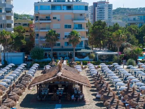 a beach with chairs and umbrellas and a building at Pampas Duplex Rooms in Durrës