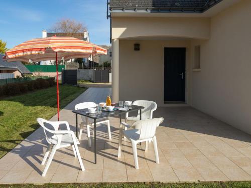 un patio avec une table, des chaises et un parasol dans l'établissement Apartment Hortensias 2 by Interhome, à Clohars-Carnoët