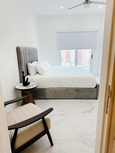 a bedroom with a bed and a chair and a window at Apartamento 3 Recamaras en MAREA Los Cabos Playa Médano CSL in Cabo San Lucas