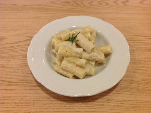 a white plate of pasta on a wooden table at Domus Australia in Rome
