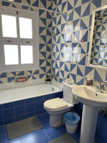 un bagno blu e bianco con un water e un lavandino di CozY Condo a Hurghada