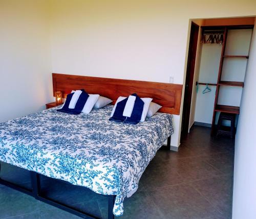 a bedroom with a bed with blue and white pillows at VILLA SIMONE ARENAL French Ecolodge in Tilarán
