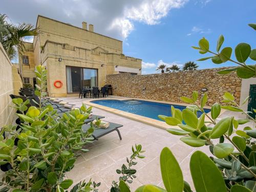 a villa with a swimming pool in front of a building at Villa Fieldview - Gozo Holiday Home in Għarb