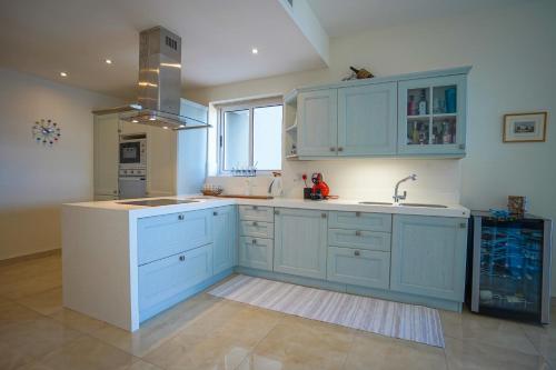 a kitchen with blue cabinets and a sink at Luxury Living Apt with Massive Pool - Views and Beautiful Gardens in Għajn Melel