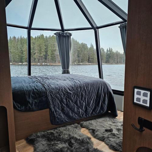 a bed on a boat with a window at Kivisalmi ja AuroraHut in Viitasaari