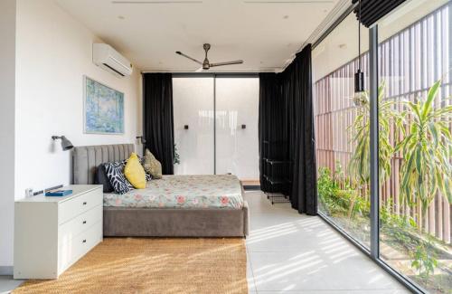 a bedroom with a bed and a large window at Reve Villa A, Dabolim Airport, Bogmalo Beach in Chicolna