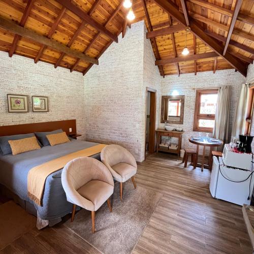 a bedroom with a bed and a table and chairs at Chale Villa do Valle in Monte Verde
