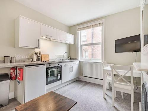 a kitchen with white cabinets and a table and a window at Coastal Apartment with Sea View 2 Minutes from Beach and Town Center in Cromer