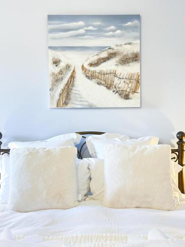 a bed with white pillows and a picture of a beach at Château de Tilly in Boissey-le-Châtel