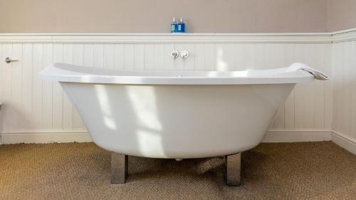 a white bath tub sitting in a room with a wall at The Sibson Inn Hotel in Water Newton