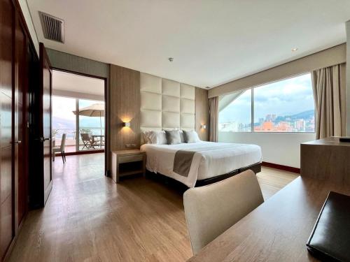 a hotel room with a bed and a large window at Hotel San Fernando Plaza in Medellín