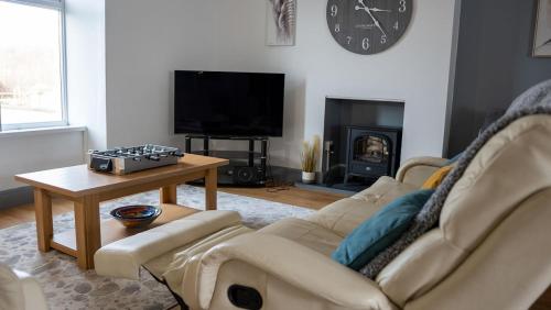 a living room with a couch and a table and a tv at 3 bedroom home by the beach in Broad Haven