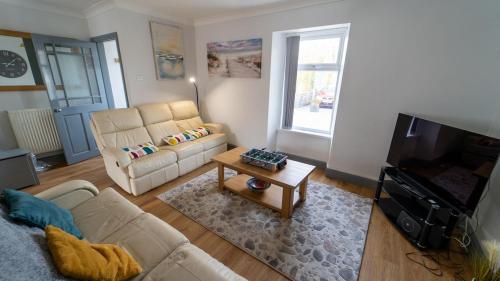 a living room with a couch and a table at 3 bedroom home by the beach in Broad Haven