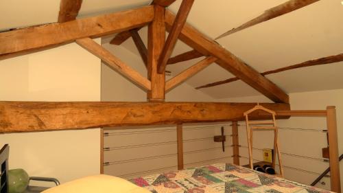 a room with a wooden ceiling with a bed and a ladder at Plaine et Colline Chambres et table d'hôtes Isère in Gillonnay