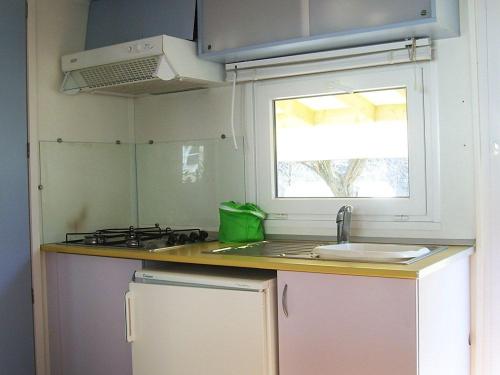 une petite cuisine avec un évier et une fenêtre dans l'établissement Camping La Charderie, à Pont-de-Labeaume