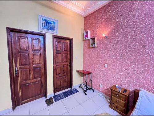 a room with a wooden door and a pink wall at Chic Shop House in Abomey-Calavi
