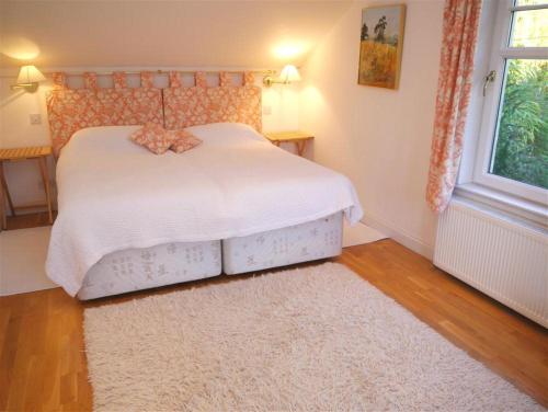 a bedroom with a white bed and a white rug at Elm Cottage in Kippford