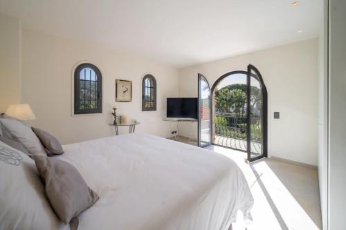 une chambre blanche avec un lit et une télévision dans l'établissement Beautiful 4 bedroom villa with pool in Cannes center, à Cannes
