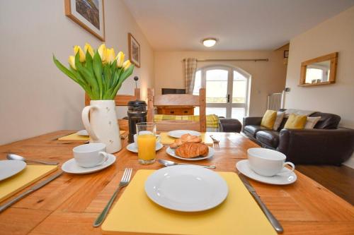 a table with plates and cups and a vase with flowers at Romantic Escape and Stargazer's Hideaway nr Dark Sky, Alnwick, Kielder in Alnham
