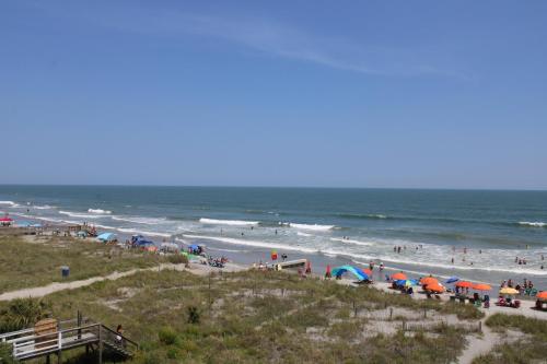 a beach with people and umbrellas and the ocean at Sand Castle in the Sky in Folly Beach