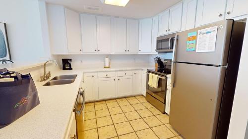 a kitchen with white cabinets and a stainless steel refrigerator at Seaside Villas 202 in Folly Beach