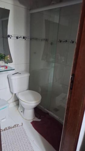 a bathroom with a toilet and a glass shower at Casa centro Cabo Frio 300 metros Praia do Forte in Cabo Frio