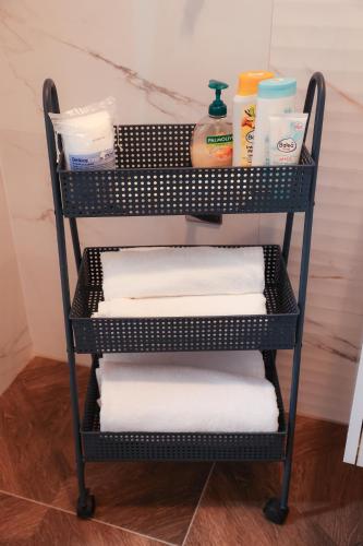 a rack with towels and cleaning products in a bathroom at Apartman Mint&White Borik in Banja Luka