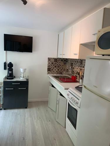 une petite cuisine avec des armoires blanches et un micro-ondes dans l'établissement Résidence la Jonquière, à Cazaubon