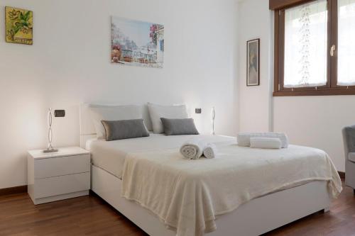 a white bedroom with a bed with two towels on it at Casa Angy in Como