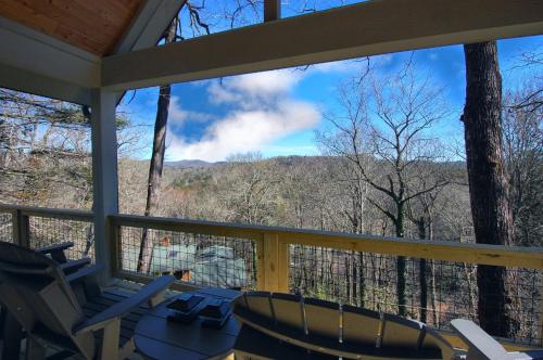 a screened in porch with chairs and a view of the mountains at The Owlery in Highlands