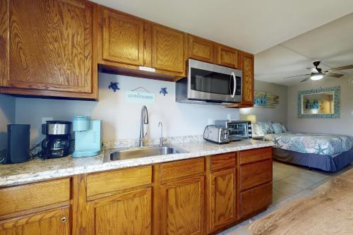 a kitchen with wooden cabinets and a sink with a microwave at Beachview 205 in Gulf Shores