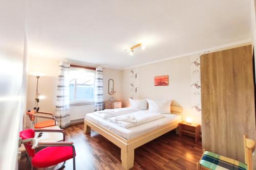 a bedroom with a white bed and a red chair at Ferienwohnung Franke 1 3 in Zinnowitz