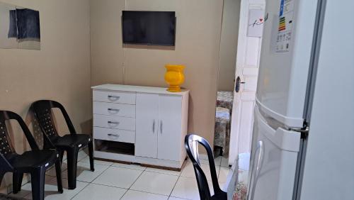 a kitchen with chairs and a white dresser and a refrigerator at Recanto da vó Maria in Ilha Rasa