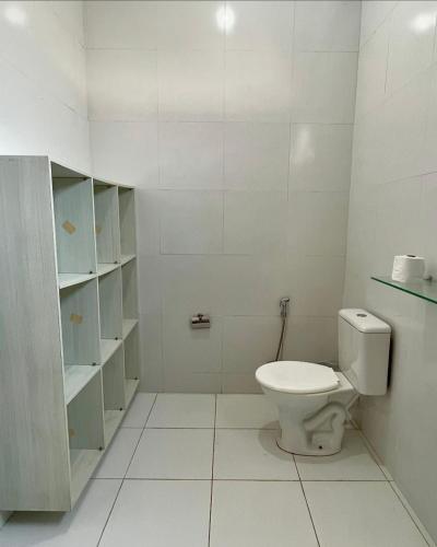 a white bathroom with a toilet and shelves at LA VITRINE Hotel in São Gabriel da Cachoeira
