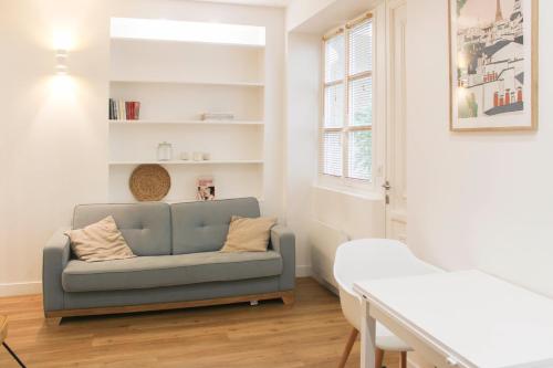 un salon avec un canapé et une fenêtre dans l'établissement Charming apartment in the heart of the 18th, à Paris