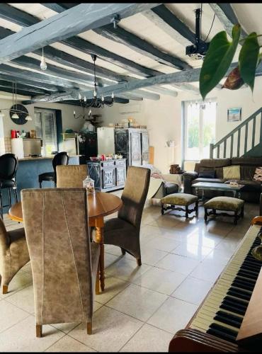 - un salon avec une table, des chaises et un piano dans l'établissement MAISON DE CHARME piscine chauffée, à Carlux